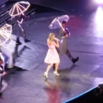 Singer performing with dancers and lit umbrellas
