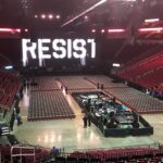 Arena stage with 'RESIST' displayed in lights.