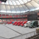 Rows of fire trucks lined up inside a large stadium.