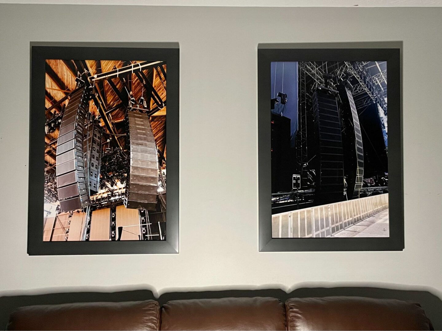 Two framed architectural photos hang above a brown leather couch.