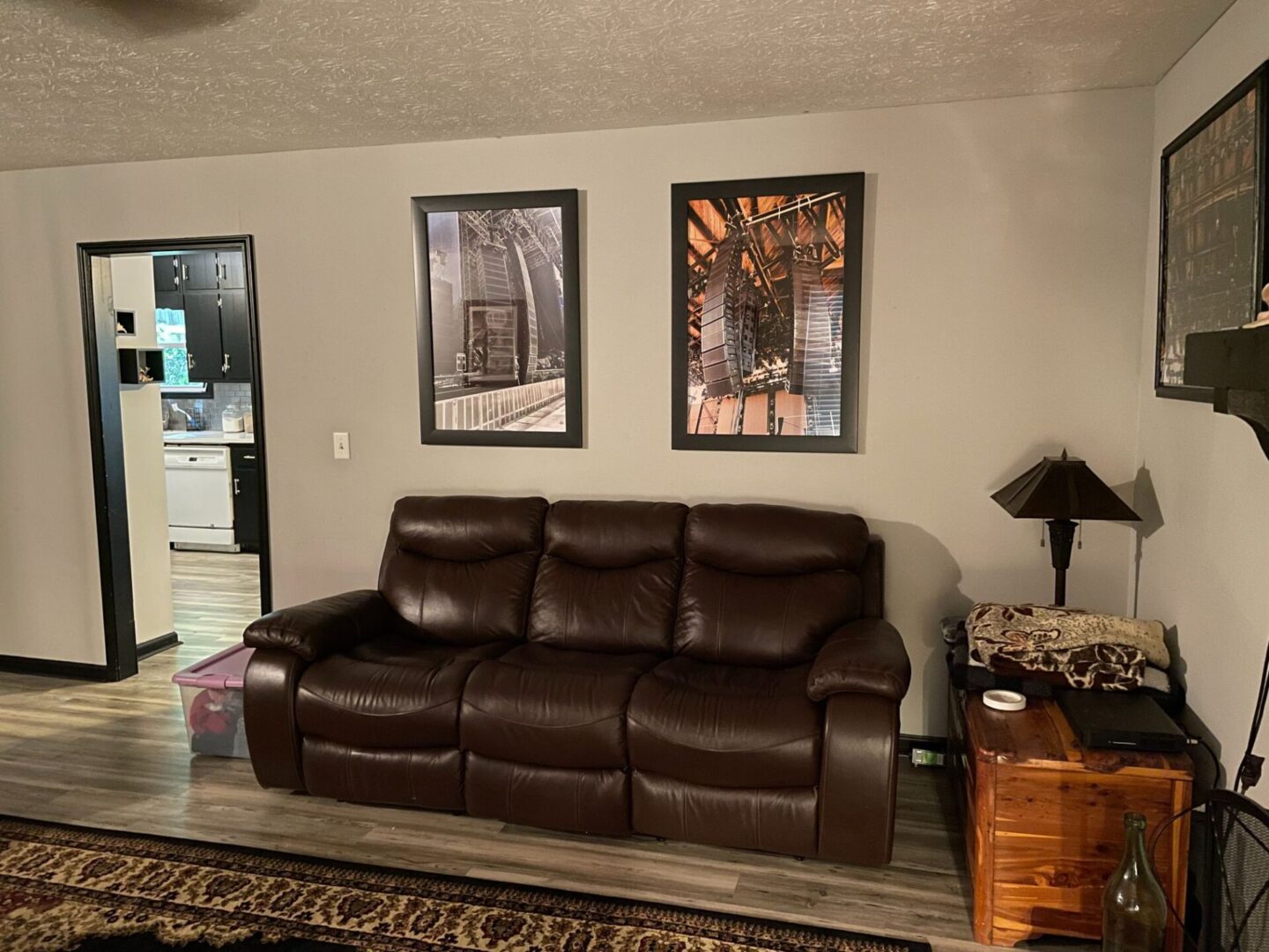 Cozy living room with brown leather couch and framed art on the wall.