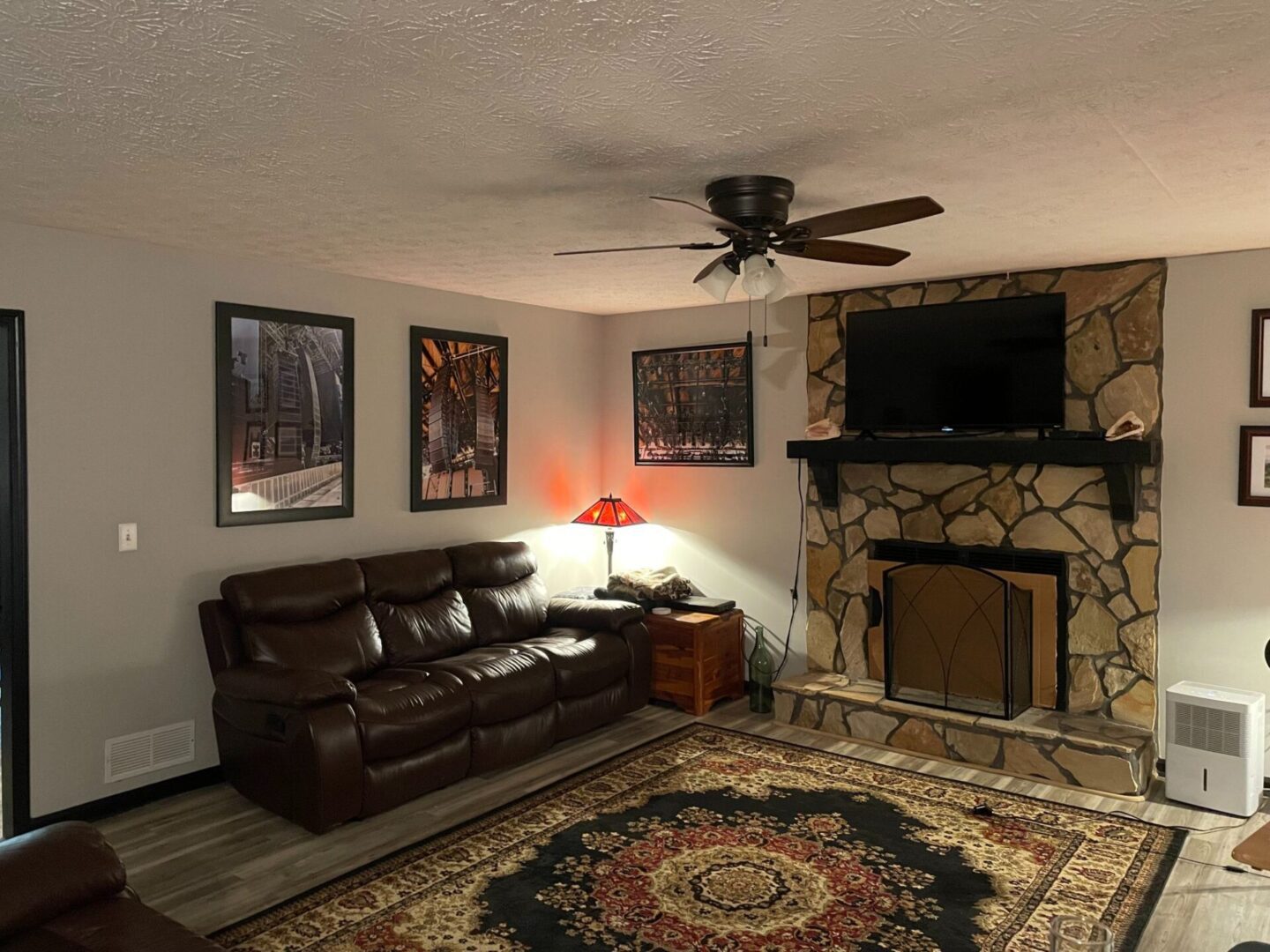 Cozy living room with leather couch, fireplace, and wall art.