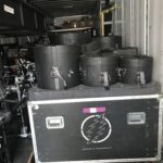 Stack of black cylindrical containers on a road case inside a truck.