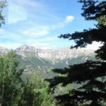 Mountain landscape with green trees and clear blue sky.