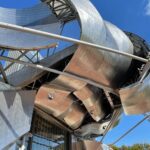 Close-up of a metallic, futuristic architectural structure under a clear blue sky.