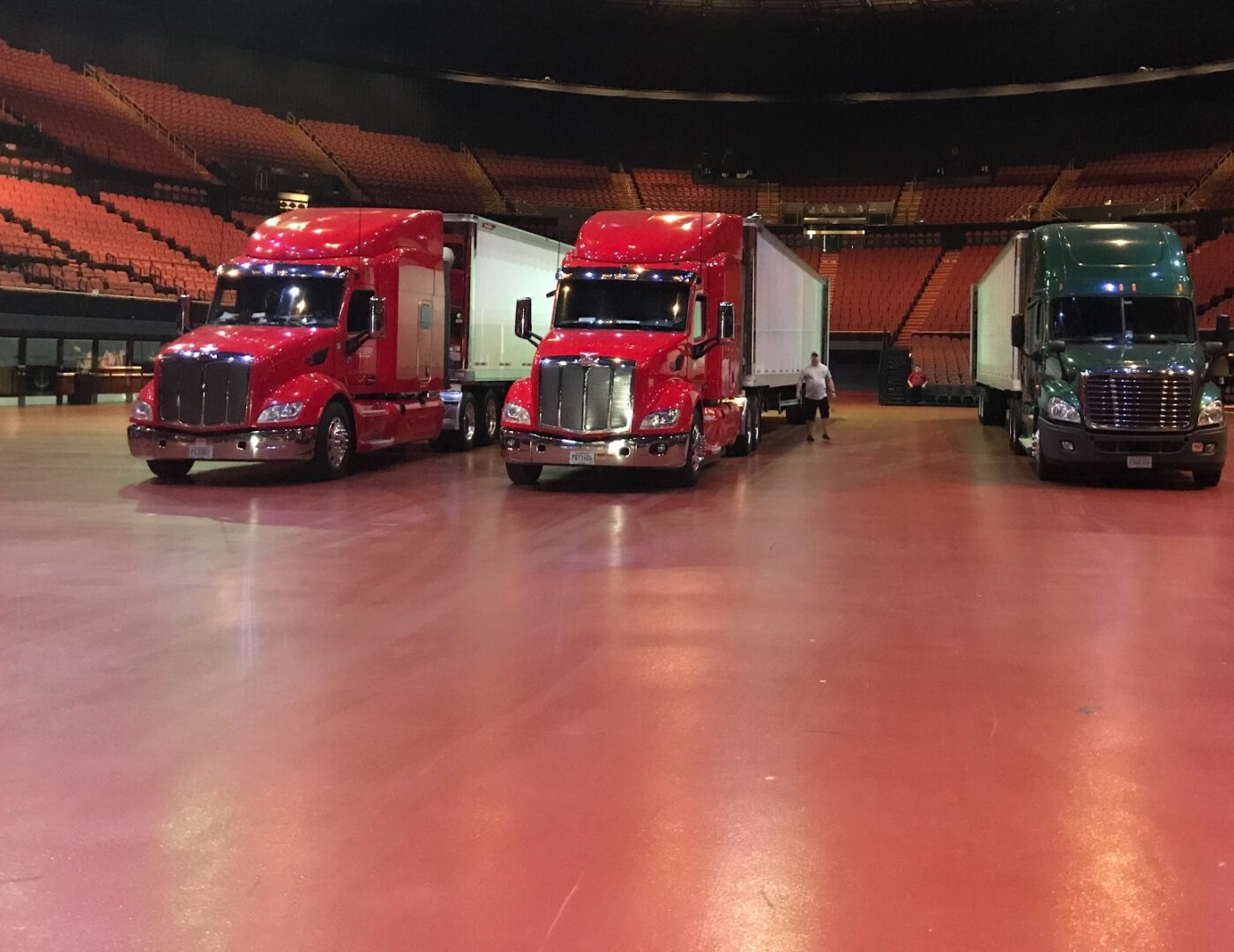 Three semi-trucks parked indoors on a polished floor.