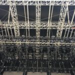 Intricate metal framework and lighting setup on a large stage ceiling.