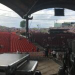 View from a stage showing rows of empty red seats in an outdoor venue.