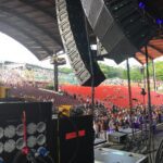 View from stage showing large crowd and sound equipment under a covered venue.