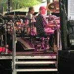 Musician playing drums on stage during a live performance.