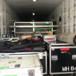 Stacked equipment cases and musical instruments in a backstage corridor.