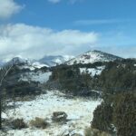 Snow-covered mountain landscape under a blue sky with scattered clouds.