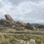 Rocky outcrop under a cloudy sky in a grassy landscape.