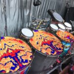 Colorful drumheads with swirling abstract patterns on a stage setup.