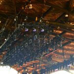 Rows of stage lights and equipment hanging from a ceiling rig.