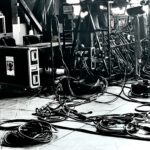 Black and white photo of a stage floor cluttered with cables and equipment cases.