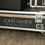 A musical equipment case labeled 'John Mayer Musical Sound'.
