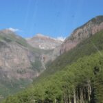 Mountainous landscape with a waterfall and green forest.