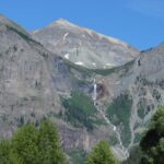Mountain landscape with a waterfall under a clear blue sky.