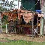 Rustic outdoor shelter with a worn tarp roof and simple wooden structure.