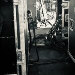 Black and white backstage scene with cables and a person reflected in a mirror.
